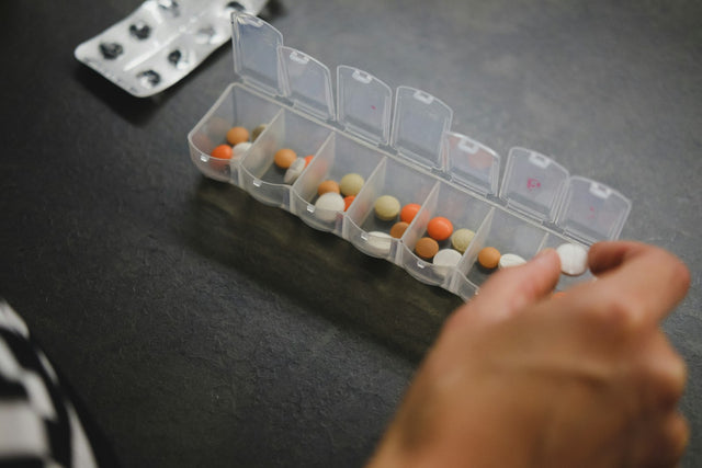 Persona organizando medicamentos en un pastillero
